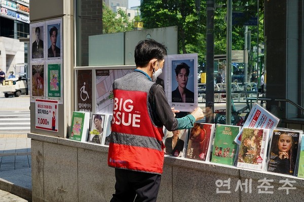 ▶▶ 송씨가 판매 준비를 위해 잡지 포스터를 붙이고 있다.