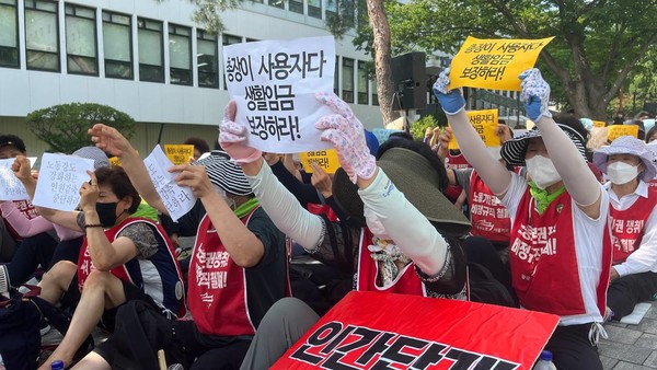 ▶▶ 우리대학교 청소노동자들이 플래카드를 들고 바닥에 앉아있다. 민주노총 공공운수노조 서울지부 연세대분회 제공